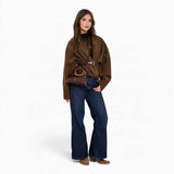 Wine ring handle crossbody bag carried in hand by a model in an everyday outfit