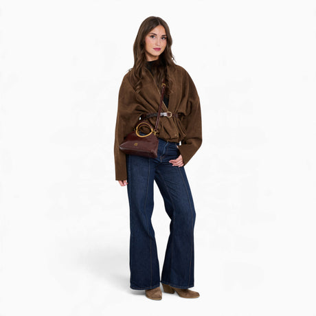 Wine ring handle crossbody bag carried in hand by a model in an everyday outfit