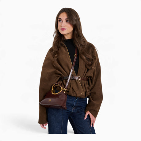 Wine ring handle crossbody bag worn across the body on its detachable strap