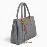 Grey small monogram tote bag, angled view showing the monogram print and charm