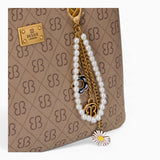 Tan monogram grab bag, close-up of the bag charm and monogram print