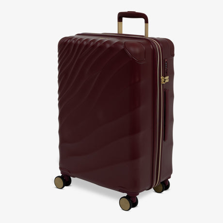 Burgundy Dusk Sahara medium suitcase, angled view showing the wave-design shell