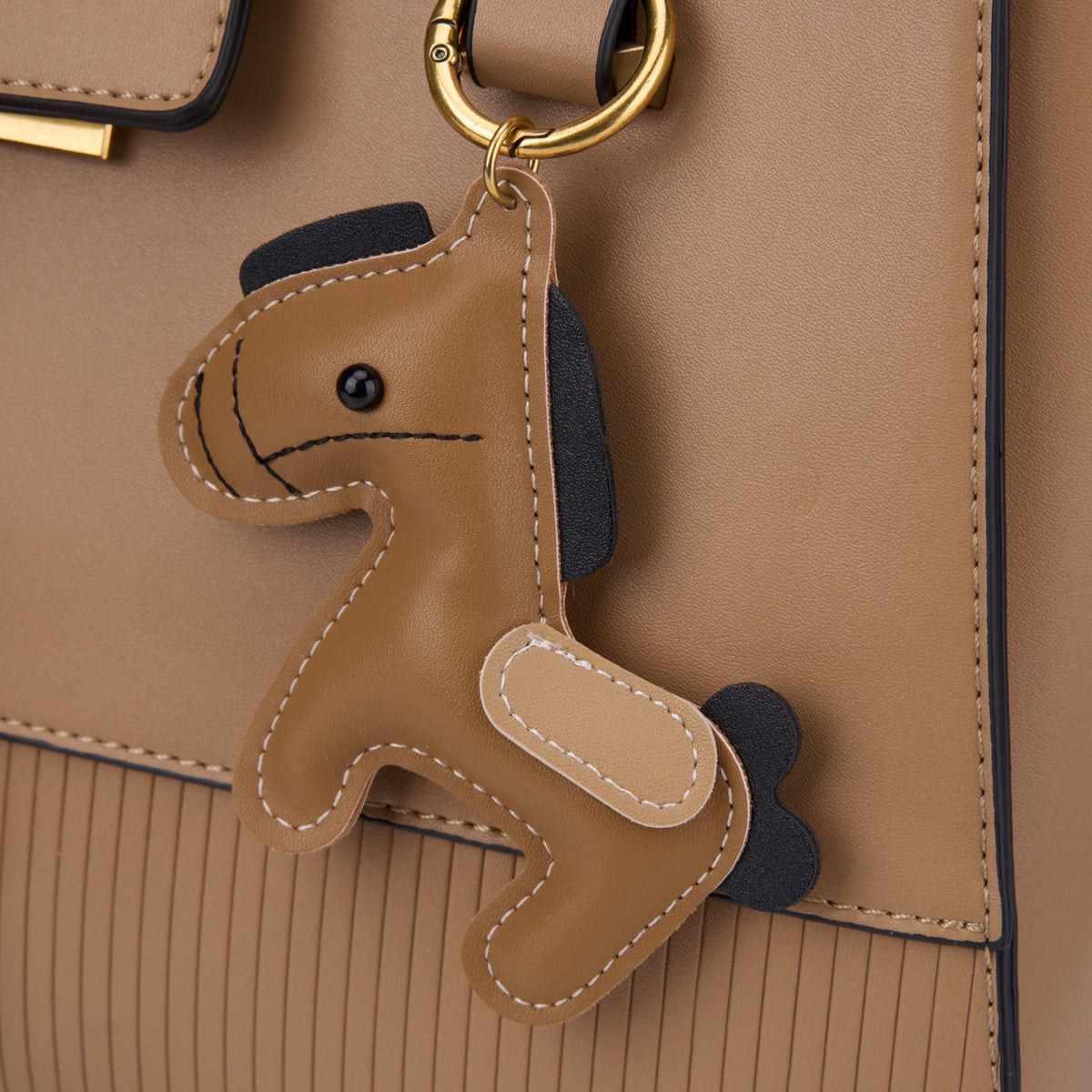 Bag Shack Bessie London tan synthetic leather tote handbag featuring a whimsical horse-shaped charm and gold hardware